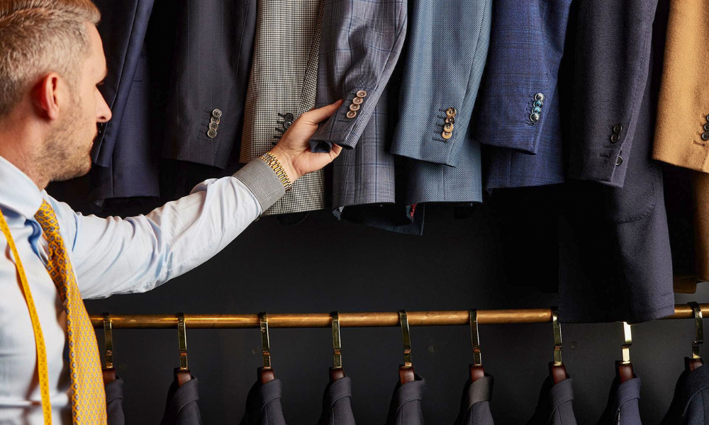 man inspecting suits in shop